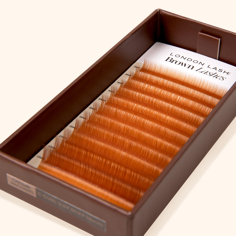 tray of lashes on beige background with caramel brown lash card inside