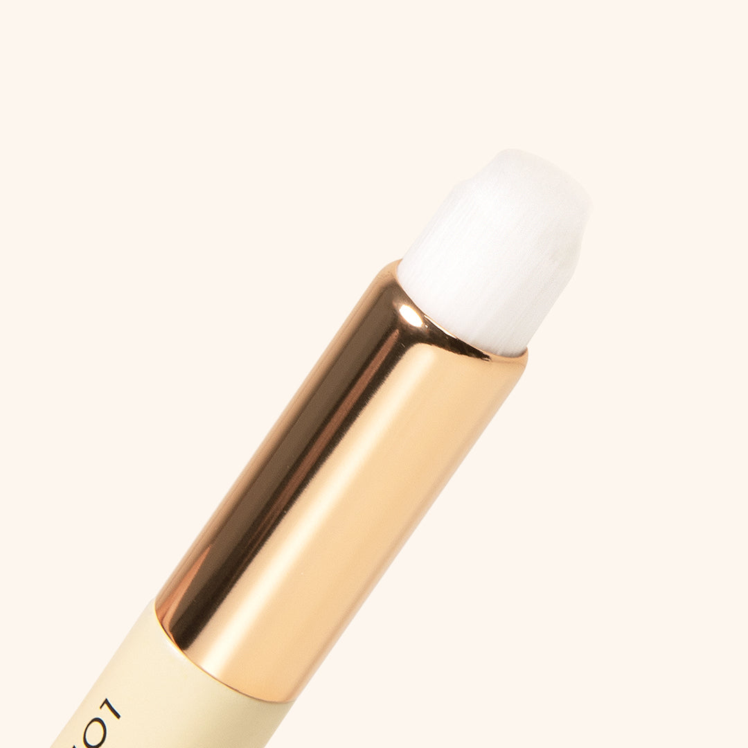 close up to the tip of the cleansing brush with gold metallic handle and white fiber brush