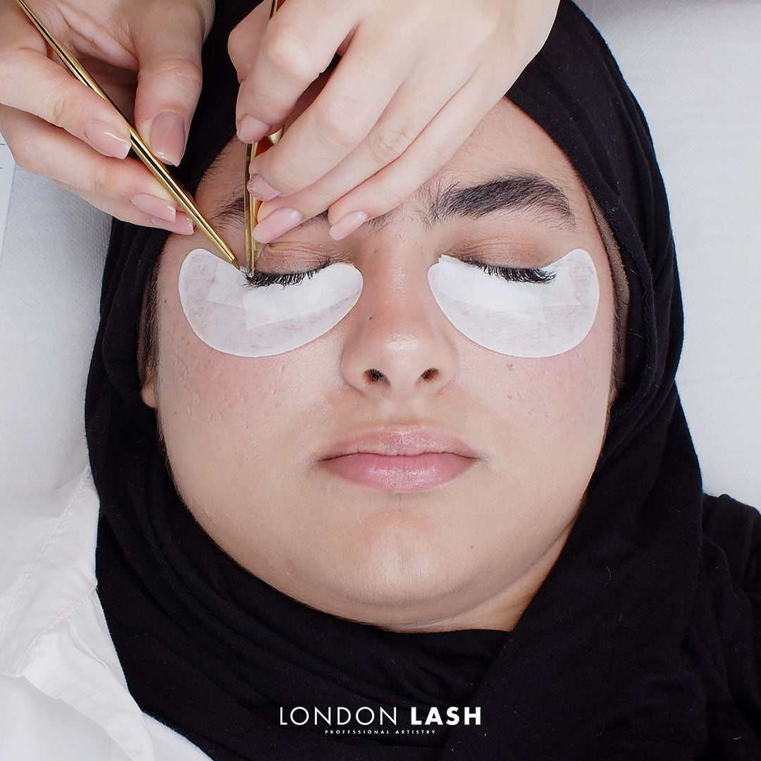 close up to woman's face with her eyes closed while getting eyelash extensions treatment