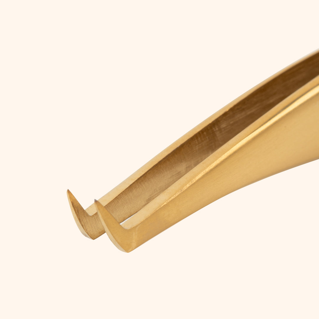 gold premium Japanese stainless steel tweezers close up to the thin curved tip